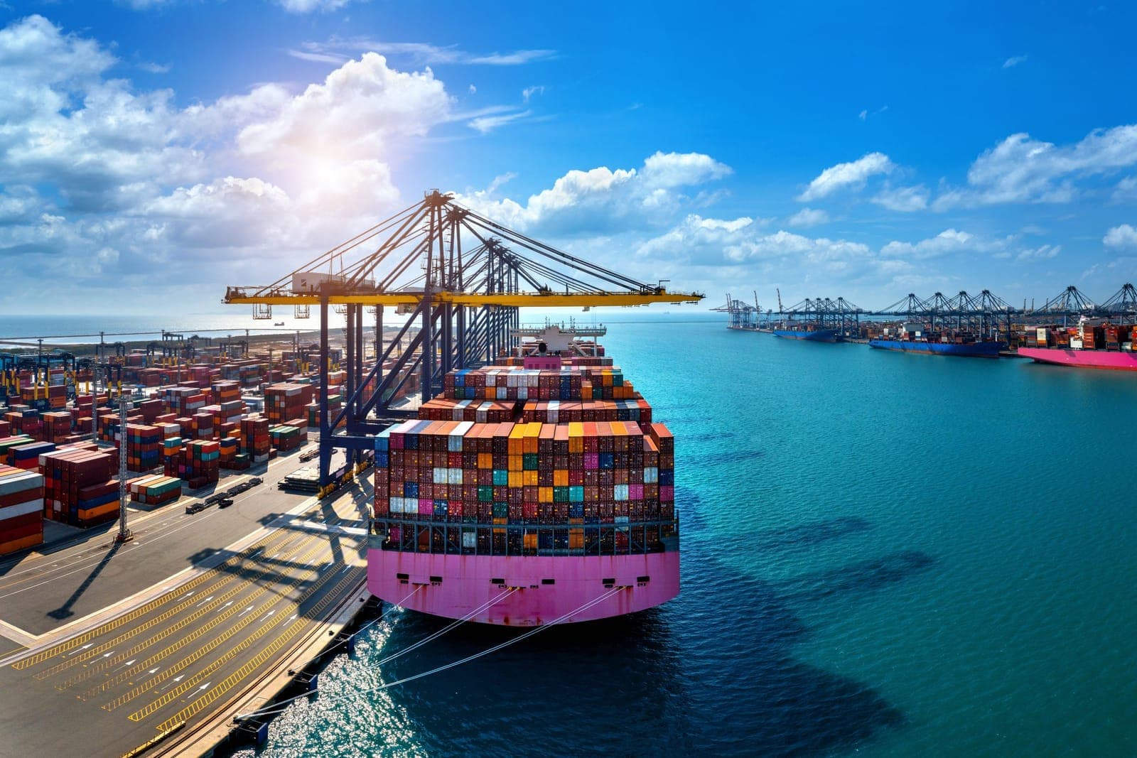 Buque portacontenedores en cargue con grúas pórtico en el muelle, escenario de los corredores portuarios de Barranquilla, Cartagena y Buenaventura.