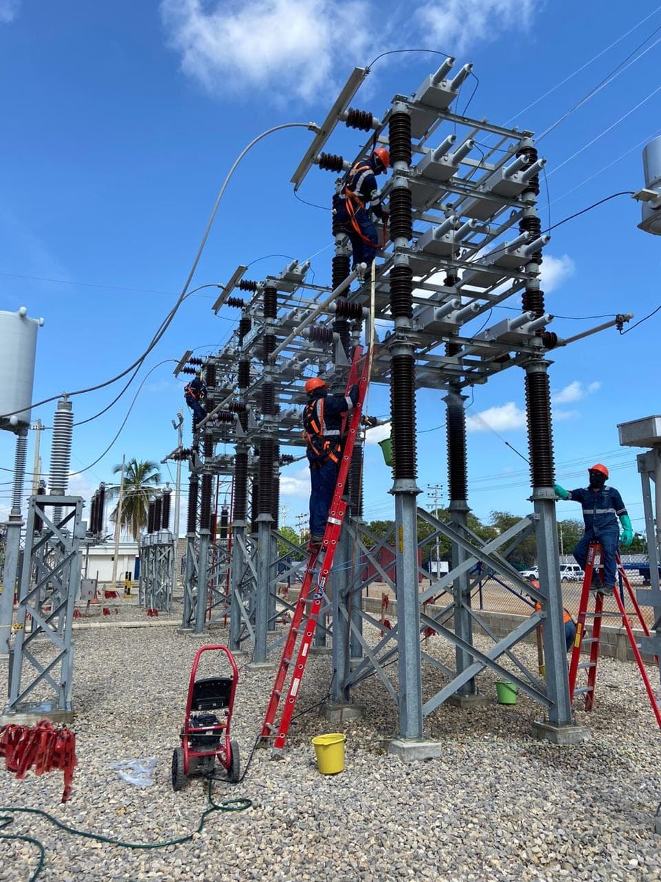 Técnicos de Grupo S&M con arnés y escaleras dieléctricas en pórticos de una subestación